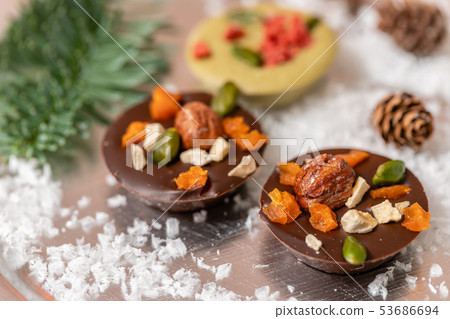Christmas theme. Handmade chocolates candy. Mini chocolate dessert covered with nuts and dried Christmas theme. Handmade chocolates candy. Mini chocolate dessert covered with nuts and dried 53686694