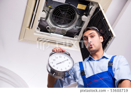 Young repairman repairing ceiling air conditioning unit  53688719