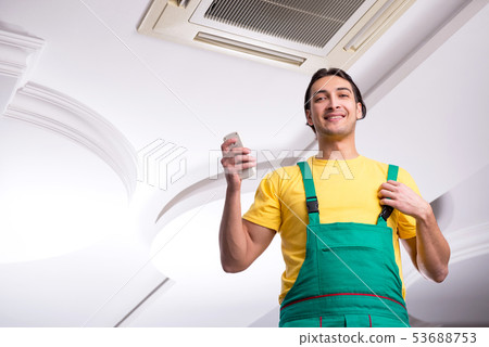 Young repairman repairing ceiling air conditioning unit Young repairman repairing ceiling air conditioning unit 53688753