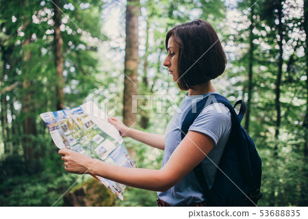 Woman looking at the map while hiking in forest. 53688835