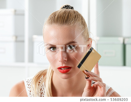 Beautiful blonde woman holding golden credit card  53689203