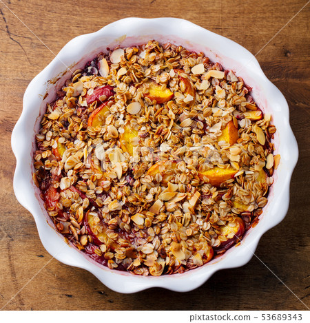 Berry, peach crumble, crisp in a baking dish. Wooden background. Top view. 53689343