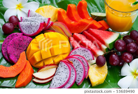Tropical fruits assortment with fresh juice, palm leaf background. Top view. Close up. 53689490