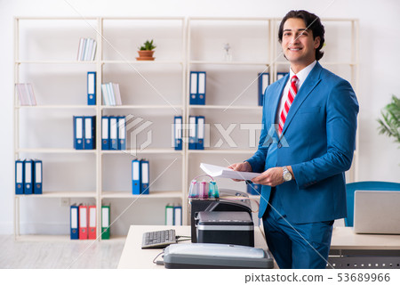 Young employee making copies at copying machine Young employee making copies at copying machine 53689966