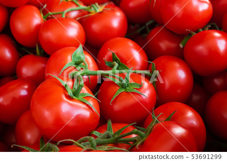 Many red tomatoes on the market. 53691299