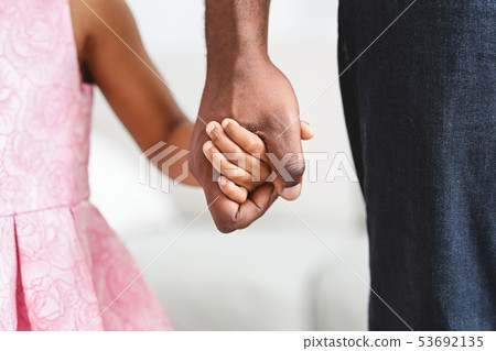 Black father taking his little daughter gently by the hand Black father taking his little daughter gently by the hand 53692135