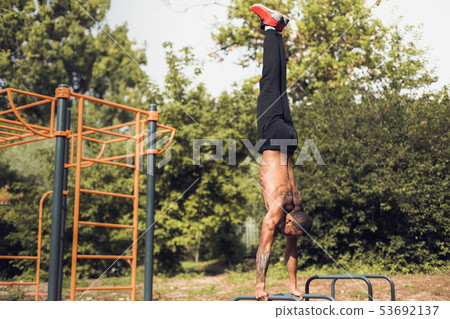 Bodyweight Exercise. Man Standing On Hands And Doing Push Ups Bodyweight Exercise. Man Standing On Hands And Doing Push Ups 53692137