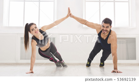 Active couple standing in plank and giving high five with one ha 53692139
