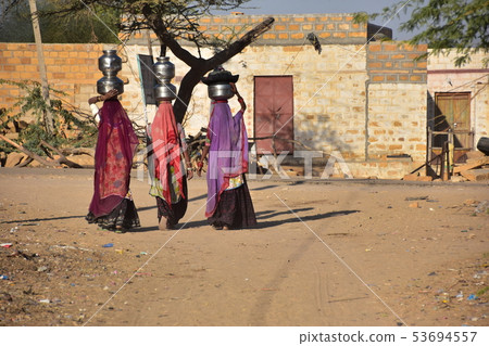 印度齋沙默爾的Cooley村婦女攜帶美麗的紗麗攜帶水瓶在他們的頭上 53694557