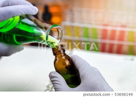 Researcher is pouring chemicals into bottles. Researcher is pouring chemicals into bottles. 53698149