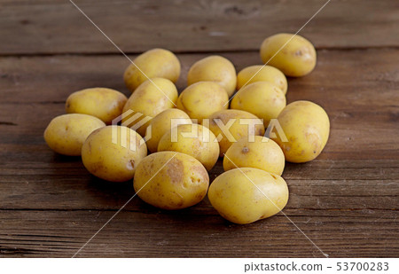 Young small potatos on wooden background Young small potatos on wooden background 53700283