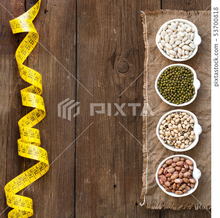 Assortment of legumes in bowls on wooden table 53700818