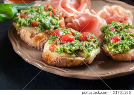Bruschetta with fresh pesto, mozzarella and cherry Bruschetta with fresh pesto, mozzarella and cherry 53701156