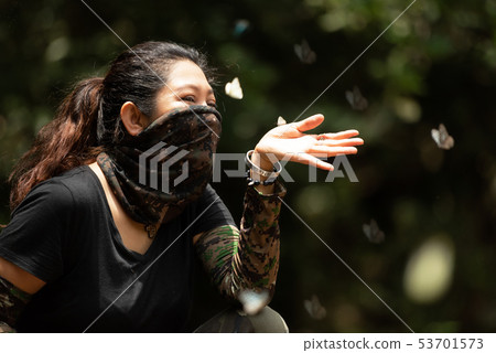 Hiker woman playing with a butterfly  53701573