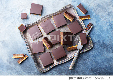 Chocolate caramel slices, bars, millionaires shortbread on a vintage tray Blue background. Top view. 53702093