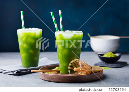Matcha, green tea ice tea, cocktail in tall glass on wooden plate. Grey stone background. 53702364
