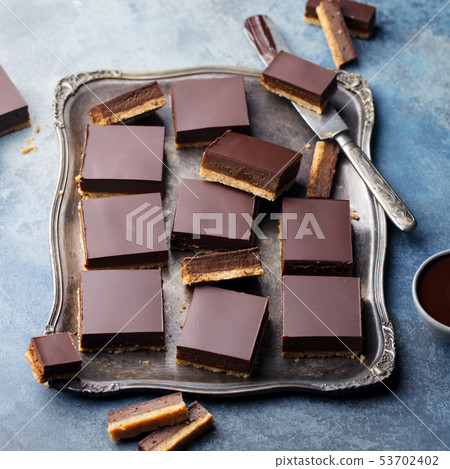 Chocolate caramel slices, bars, millionaires shortbread on a vintage tray. Blue background. Chocolate caramel slices, bars, millionaires shortbread on a vintage tray. Blue background. 53702402