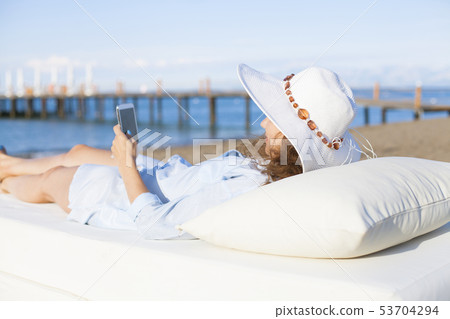 Woman using smartphone on the beach 53704294