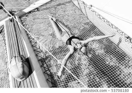 Womanin bikini tanning and relaxing on a summer sailin cruise, lying in hammock of luxury catamaran Womanin bikini tanning and relaxing on a summer sailin cruise, lying in hammock of luxury catamaran 53708180