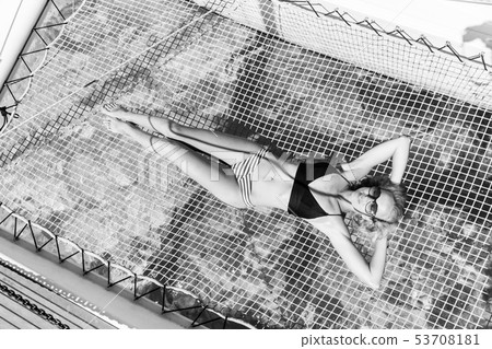 Womanin bikini tanning and relaxing on a summer sailin cruise, lying in hammock of luxury catamaran Womanin bikini tanning and relaxing on a summer sailin cruise, lying in hammock of luxury catamaran 53708181