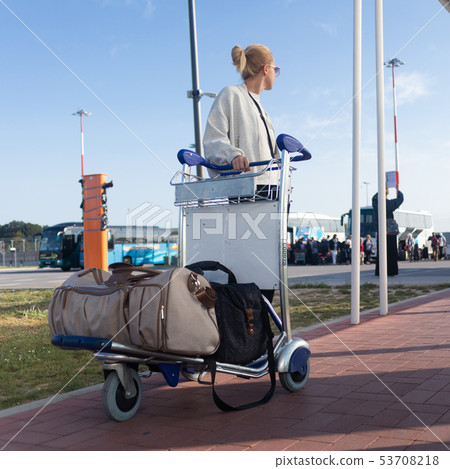 Young woman transporting luggage from arrival parking to international airport departure termainal 53708218