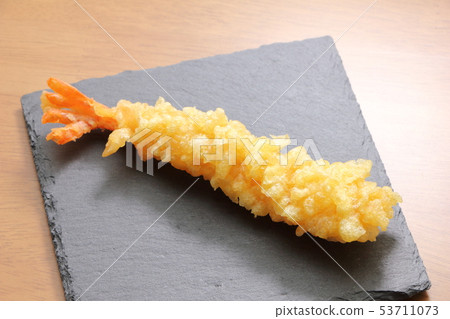 One shrimp tempura fried straight and placed on a slate plate. 53711073
