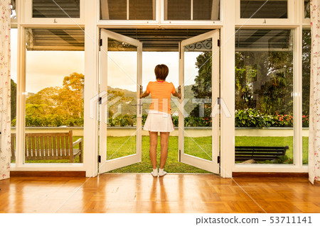 Women opening glass door to refreshing sunrise 53711141