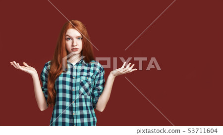 What should I do Bright emotional female portrait. Girl throws up hands with sorry face. What should I do Bright emotional female portrait. Girl throws up hands with sorry face. 53711604
