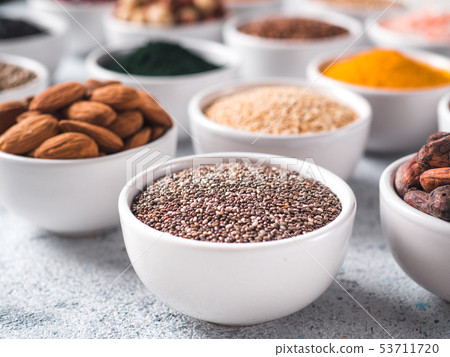 Chia seeds in small white bowl and other superfoods 53711720