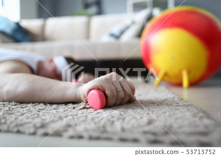 Tired Man Lying on Floor with Dumbbell in Hand 53713752