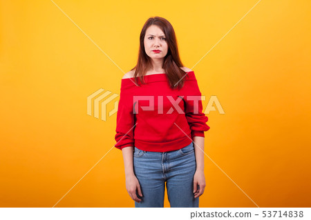 Portrait of beautiful young woman looking annoyed at the camera over yellow background 53714838
