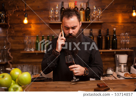 Bearded young batender talking on the phone taking care of his business. 53714857