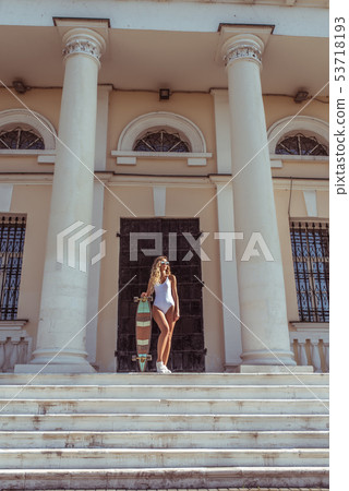 Girl in summer in the city, posing with a board, longboard skate, sunglasses white body. Fashion 53718193