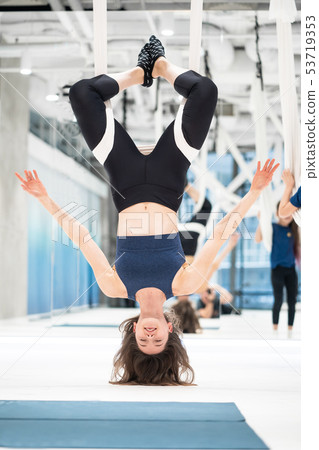 Woman hanging upside down in a hammock. Fly yoga class. Woman hanging upside down in a hammock. Fly yoga class. 53719353
