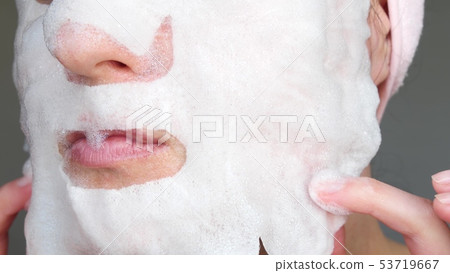 A woman apply a bubble mask for skin care. A woman apply a bubble mask for skin care. 53719667