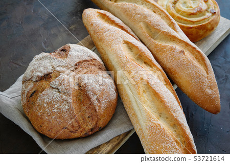 Freshly baked baguettes, bread and bun on napkin. 53721614