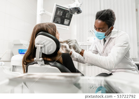 Young African male dentist with a patient. Woman in the dentist chair at dental clinic. Medicine 53722792