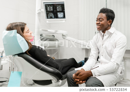 Young African male dentist with a patient. Woman in the dentist chair at dental clinic. Medicine 53722834