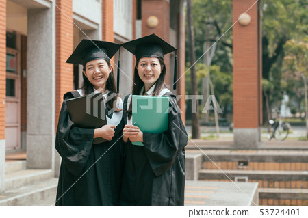 student in graduation gown cap holding textbook student in graduation gown cap holding textbook 53724401