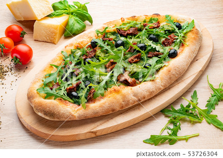 pizza with dried tomatoes and arugula on the wooden board 53726304