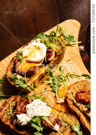 toast with dried tomatoes, poached egg and arugula leaves 53726438