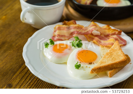 American breakfast with sunny side up eggs, bacon, toast, pancakes, coffee and juice American breakfast with sunny side up eggs, bacon, toast, pancakes, coffee and juice 53729253