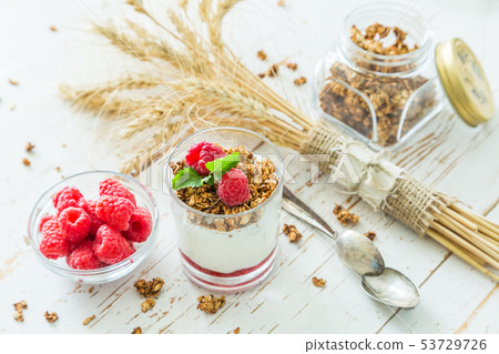 Granola with rasberry and yogurt in glass Granola with rasberry and yogurt in glass 53729726