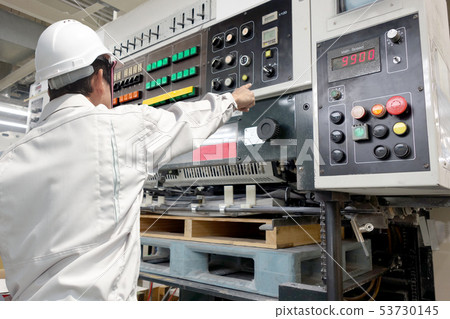 Back view of one man operating an offset printing press 53730145