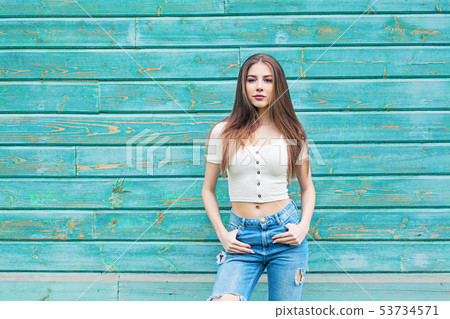 Portrait of young woman against blue background Portrait of young woman against blue background 53734571