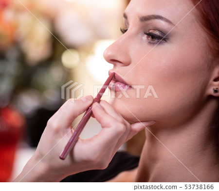 Makeup artist applies red lipstick . Beautiful woman face. Hand of make-up master, painting lips of 53738166