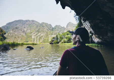 Man on boat floating through to cave Man on boat floating through to cave 53739266