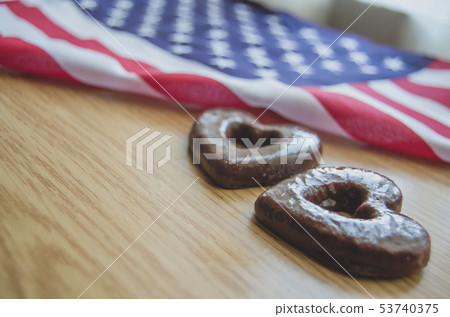 two heart shaped biscuits and usa flag on wooden table happy memorial day. two heart shaped biscuits and usa flag on wooden table happy memorial day. 53740375