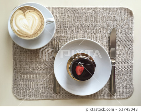 a cup of coffee and cake on table 53745048