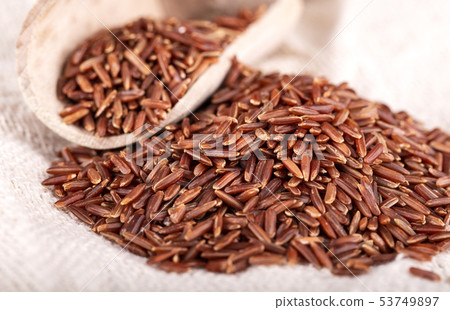 The brown rice with wooden spoon on sackcloth The brown rice with wooden spoon on sackcloth 53749897
